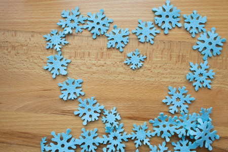 Blue snowflakes laid out in the form of heart on a wooden background.の写真素材