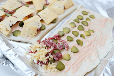 The dough on the baking sheet with the ingredients for pizzaの写真素材