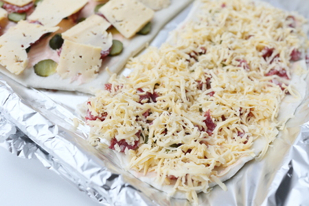 The dough on the baking sheet with the ingredients for pizzaの写真素材