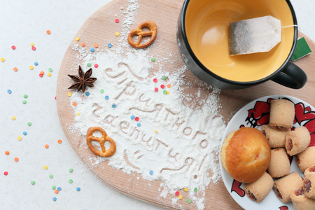Tea still life with an inscription in Russian. Mug with plate of sweets, and the inscription on the sahornoy powder.の写真素材