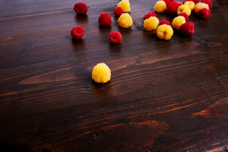 Raspberries scattered on a dark background. Red and yellow raspberries. Wooden background.