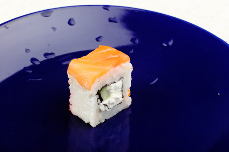 One roll of Philadelphia sushi on a blue plate.の写真素材