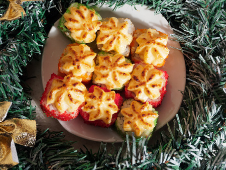 Christmas sushi. New Year sushi. Plate with baked sushi and Christmas wreath.の写真素材