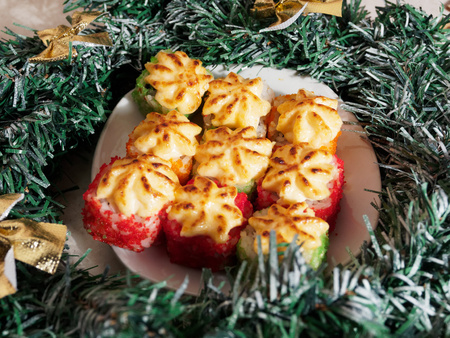 Christmas sushi. New Year sushi. Plate with baked sushi and Christmas wreath.の写真素材