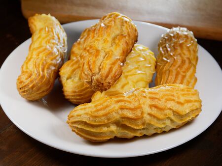 Fresh eclairs on a white plate. Delicious homemade cakes.