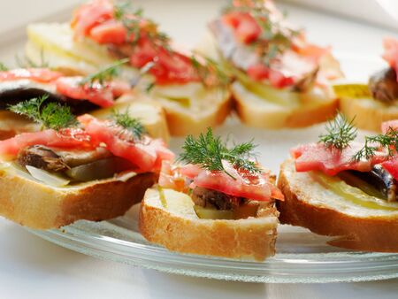 Snack sandwich with sprats cucumber and tomatoes and dill. Delicious sandwiches on a plate.の写真素材