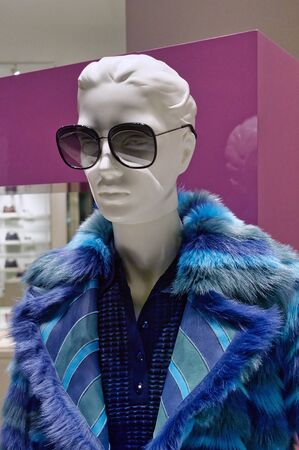 Female mannequin wearing blue coat and sunglasses in a luxury fashion storeの写真素材