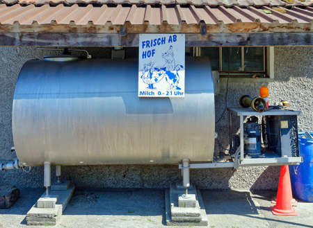 Bern, Switzerland - May 31, 2020: Dairy tank on a organic farm where fresh milk can be bought directly from the farmer. The placard contains the following text: Fresh from the farm, milk 6 am - 21 pm.のeditorial素材