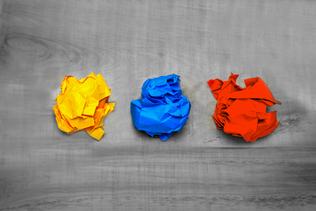 Three balls of crumpled colored paper on a wooden tableの写真素材
