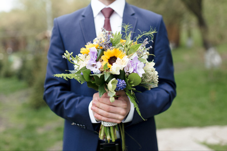 Man in blue formal suit holding a wedding bouquetの写真素材