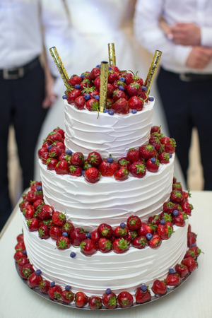 Vertical shot of a red and white wedding cake with fresh strawberries decorationの写真素材