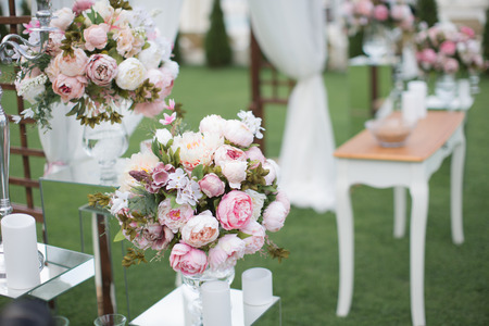 Outdoors wedding decoration with flower bouquets, candles and garlandsの写真素材