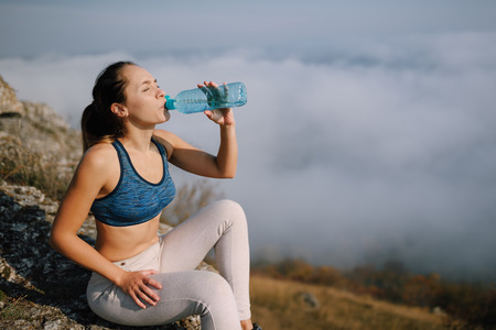 Woman in sport pants holding a bottle of waterの写真素材