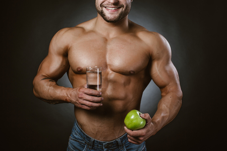 Bodybuilder with an apple and a glass of waterの写真素材