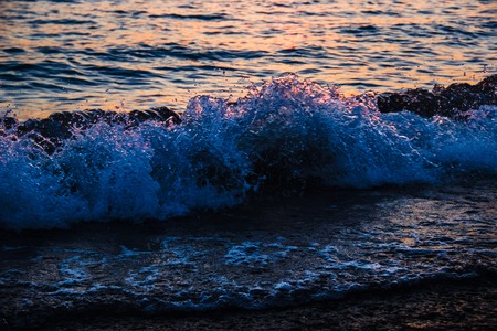 Sea waves roll to the shore at sunset