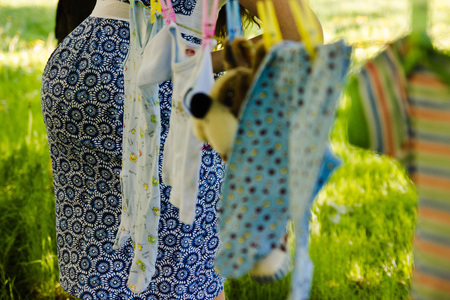 Pregnant girl. Pregnant belly. Children's clothes on a ropeの写真素材
