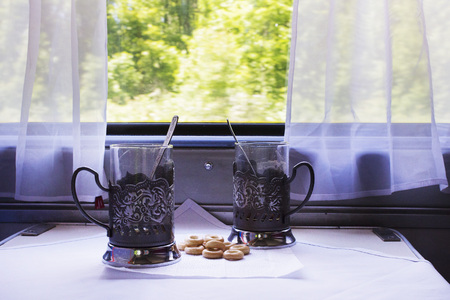 A table in the cab of the train with glasses, spoons and steering-wheel.