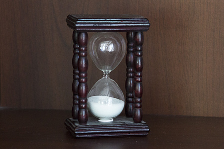 Hourglass with wooden case on wooden background