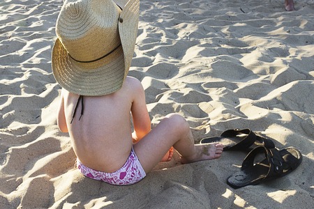 A child in a hat with sunglasses on the beachの写真素材