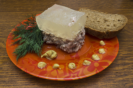 Jelly on a plate and mustard with bread and dill on rustic wooden background