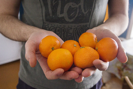A man in a shirt with ripe tangerines in his handsの写真素材