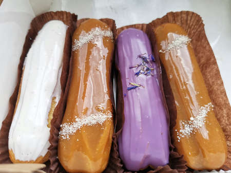 Colorful Eclairs In The Box. Eclairs Laying Inside White Boxes. Colorful Eclairs In The Box. Eclairs Laying Inside White Boxes. Eclair Cakes With Scalded Carmel And Coffee Butter Cream.の写真素材