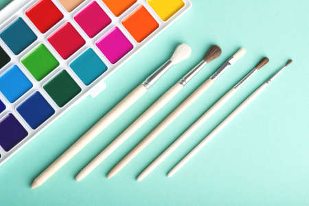 Watercolor paints and brushes on a turquoise backgroundの写真素材