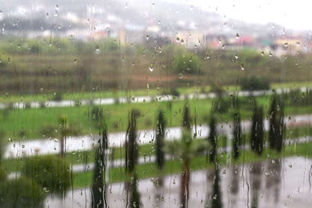 Raindrops on the window glass, bright spring greenery, houses on the mountainside. Rainy weather in a seaside town.の写真素材