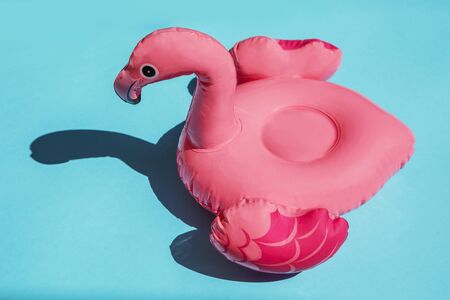 Pink flamingo swim ring drink holder on turquoise background with shadows of exotic plants. Summer , vacation conceptの写真素材