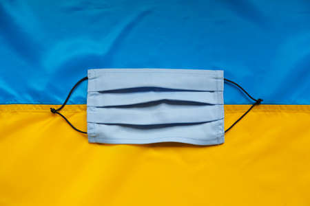 Coronavirus Covid-19 in Ukraine. Ukrainian flag on background, syringe, protective medical mask, medication or vaccine.の写真素材