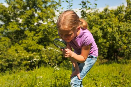 Little girl child looking through a magnifying glass. Closeup portrait on nature.の写真素材