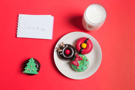 Letter, Donuts cookies and glass of milk for Santa on red background, concept Christmas and holiday.の写真素材