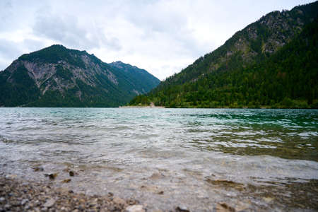 Picture over the waves of the Austrian lake Plansee. The lake is located in the middle of the alps between mountains.の写真素材