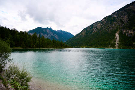 Picture over the waves of the Austrian lake Plansee. The lake is located in the middle of the alps between mountains.の写真素材