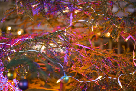 The center of a Christmas tree decorated with baubles and lights. Illuminated with red and purple colors for a special and warm feeling.の写真素材