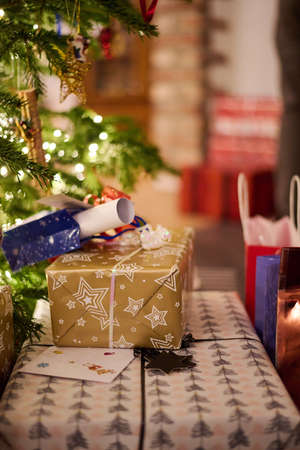 A stack of presents under the Christmas tree. With warm light in the living room.の写真素材