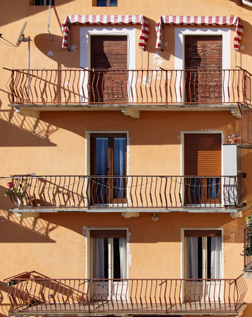 Six doors, three balconies, orange Italian facade with blindsの写真素材