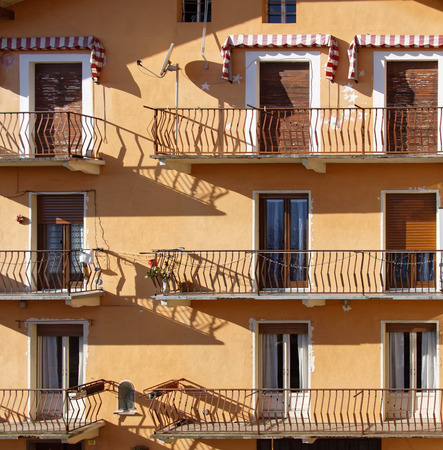 Nne doors, sixbalconies, orange Italian facade with blindsの写真素材