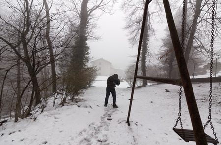 Lonely man walking and photography in the winter fog with snowy landscapeの写真素材