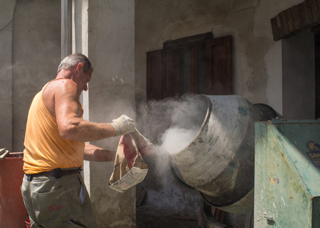 Carpenter filling the concrete mixer, man at workのeditorial素材