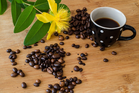 Top view of coffee beans in hearth, cup with espresso and hypericum flowers on the wooden backgroundの写真素材