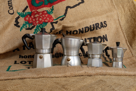 Tavigliano, Italy - August, 01, 2017: Four italian moka in vintage still life style, coffee jute bag in background.のeditorial素材