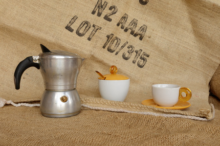 Tavigliano, Italy - August, 01, 2017: Front frame to Italian moka and coffee beans into the cup. Vintage still life style, jute bag in background.のeditorial素材