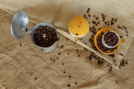 Tavigliano, Italy - August, 01, 2017: High angle frame over Italian moka and coffee beans into the cup. Vintage still life style, jute bag in background.のeditorial素材
