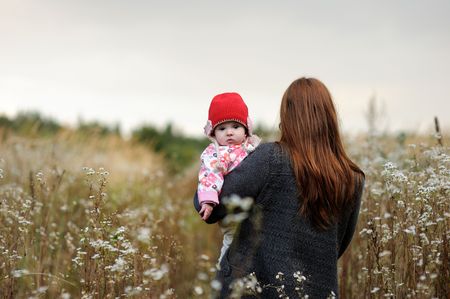 Mother holding her baby wearing red hat in armsの写真素材