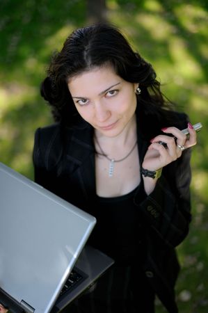 Young beautiful lady outside with a laptop and a cell phoneの写真素材
