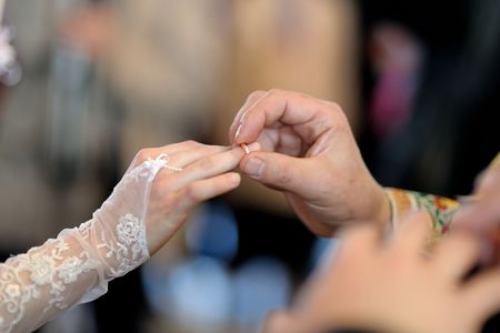 Groom is putting the ring on bride's fingerの写真素材