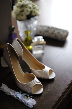 Elegant bride's shoes, garter and flowers in a backgroundの写真素材