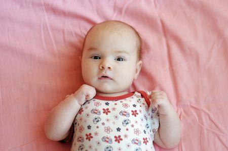 Four month old baby girl on a pink blanket