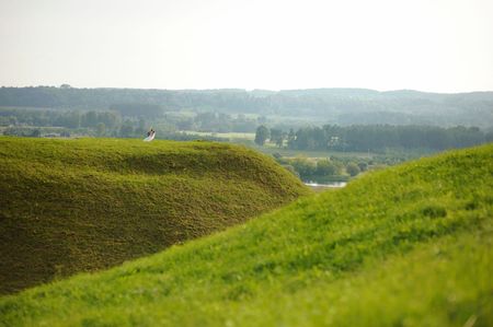 Bride and groom dancing on a green hillの写真素材